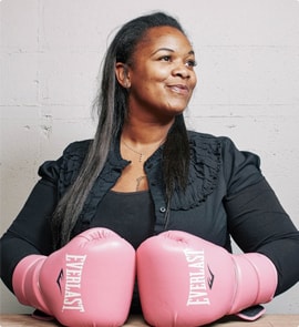 A woman wearing pink boxing gloves is posing for a photo.