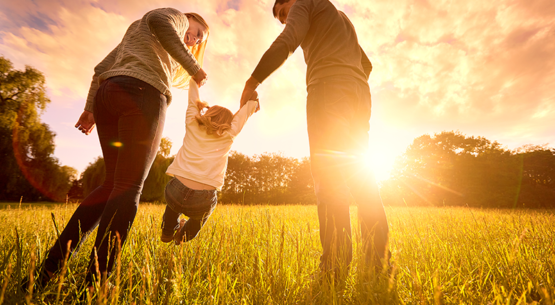 A family holding hands in a grassy field.