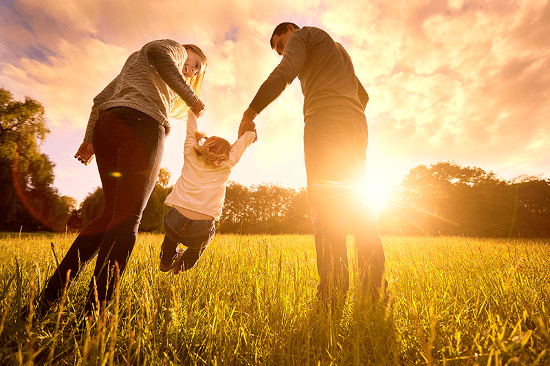 A family holding hands in a grassy field.
