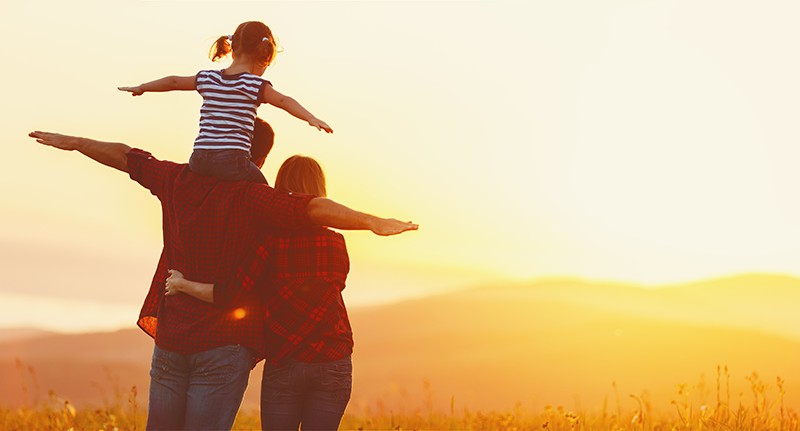 A family standing on the shoulders of each other in the middle of a field.