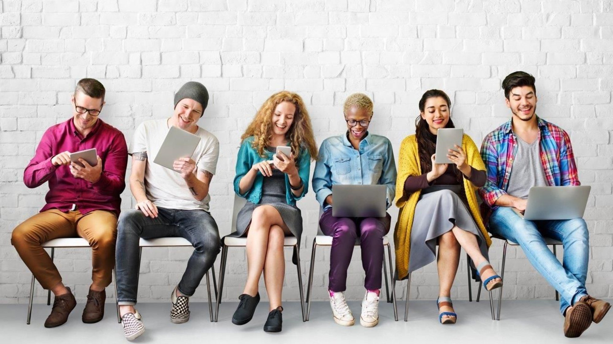 A group of people sitting on chairs and using laptops.